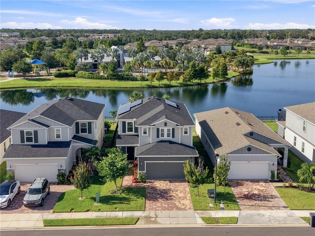 An aerial view shows three suburban houses with paved driveways facing a lake — 11447 GALLATIN TRAIL, PARRISH, FL