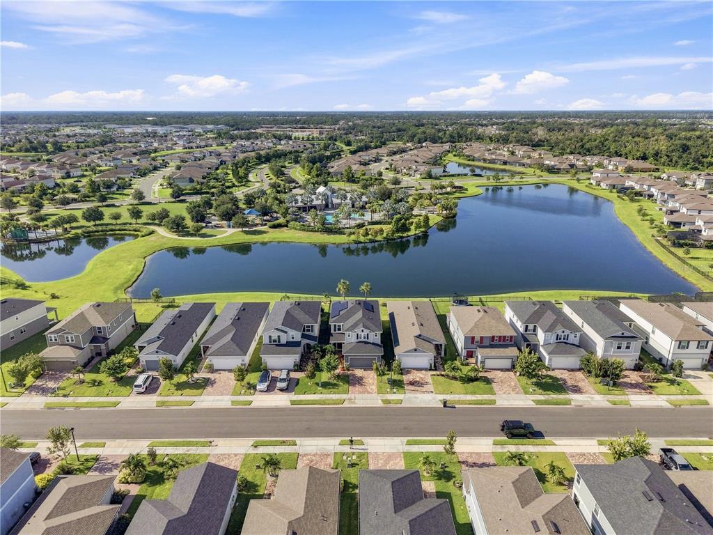 An aerial view shows a row of suburban houses facing a large lake and community center — 11447 GALLATIN TRAIL, PARRISH, FL