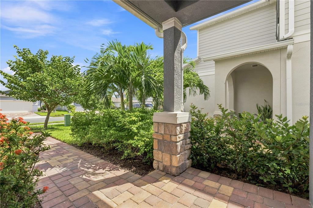 A paved walkway leads to a covered front porch with a stone-based pillar and landscaping — 11447 GALLATIN TRAIL, PARRISH, FL