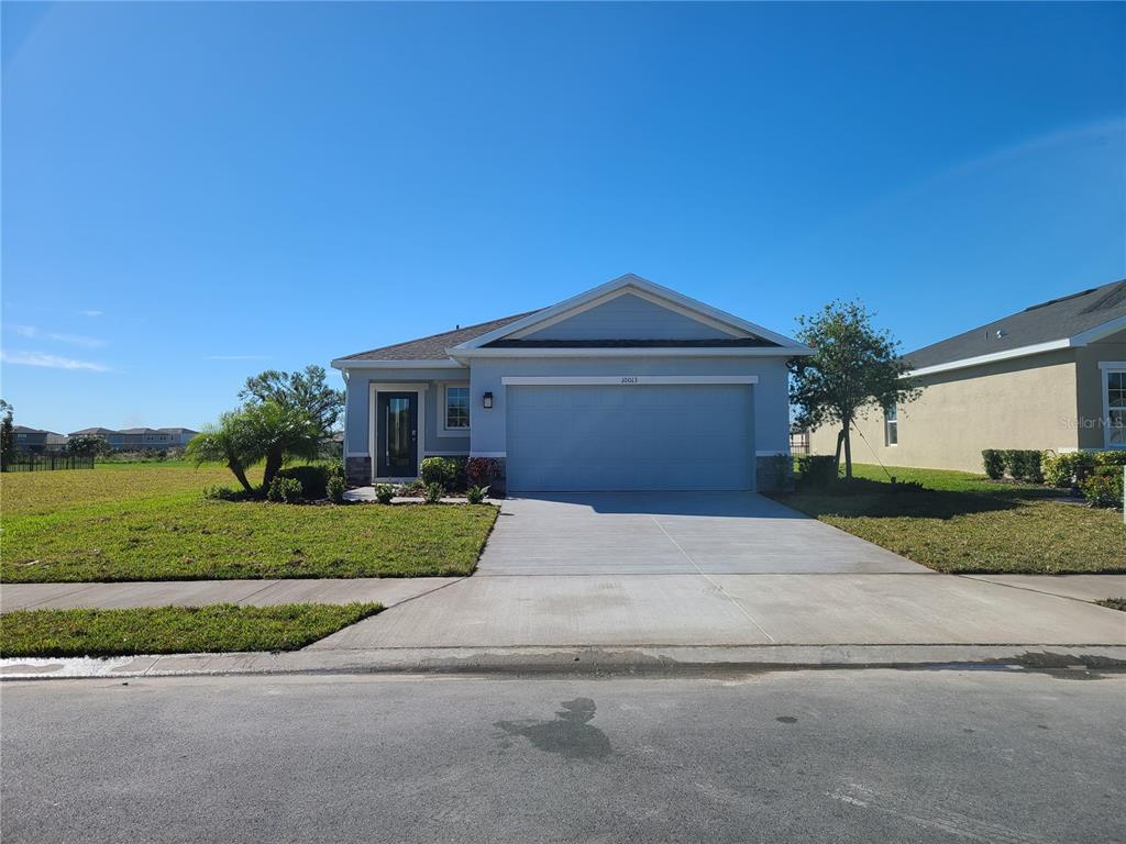 A single-story house with a light blue exterior, a two-car garage, and a concrete driveway — 10013 DAYBREAK GLEN, PARRISH, FL
