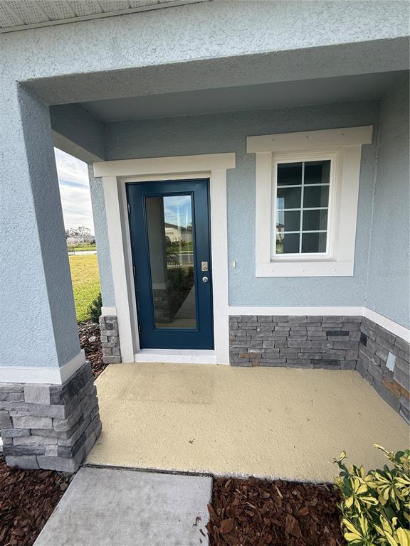A blue front door and window are set into a light blue stucco exterior wall — 10013 DAYBREAK GLEN, PARRISH, FL