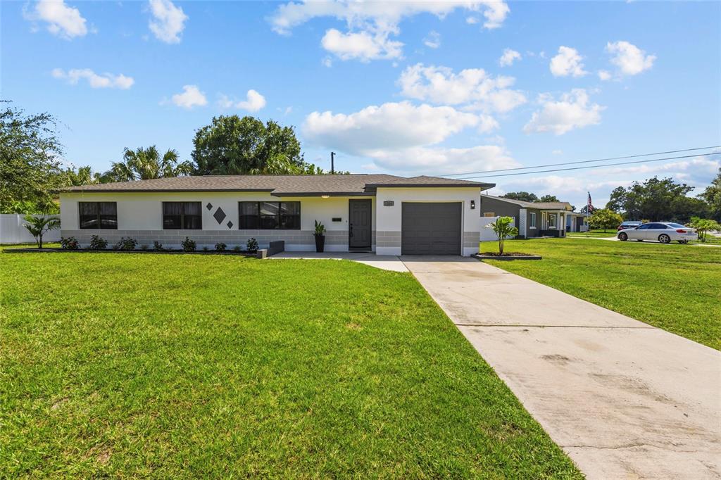 A single-story house with a gray garage, white exterior, and a concrete driveway — 1200 63RD AVENUE N, ST PETERSBURG, FL