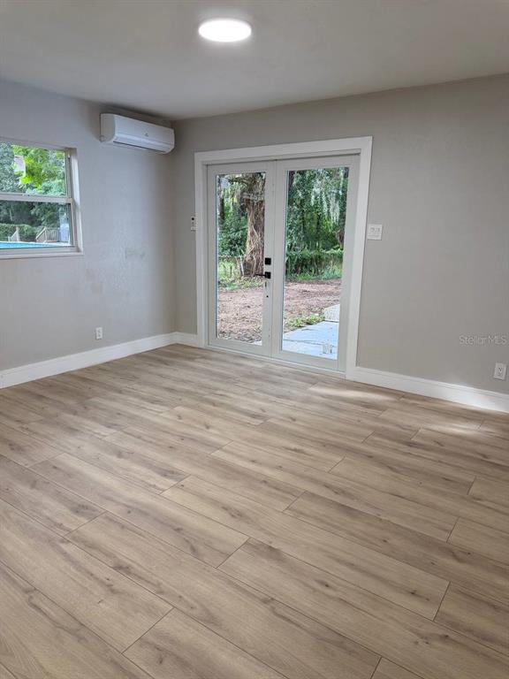 An empty room features light wood-look flooring, a mini-split air conditioner, and glass French doors — 924 VALMAR ST, BRANDON, FL