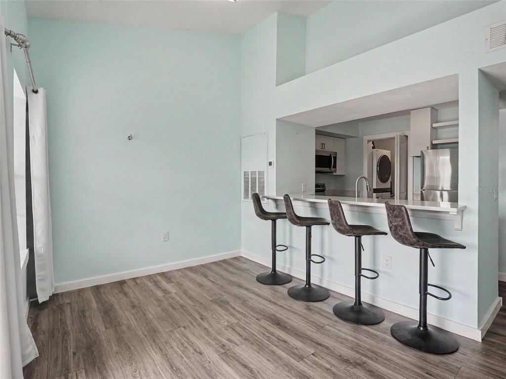 A kitchen breakfast bar with four stools sits in a room with light blue walls — 5144 CITY STREET UNIT 233, ORLANDO, FL