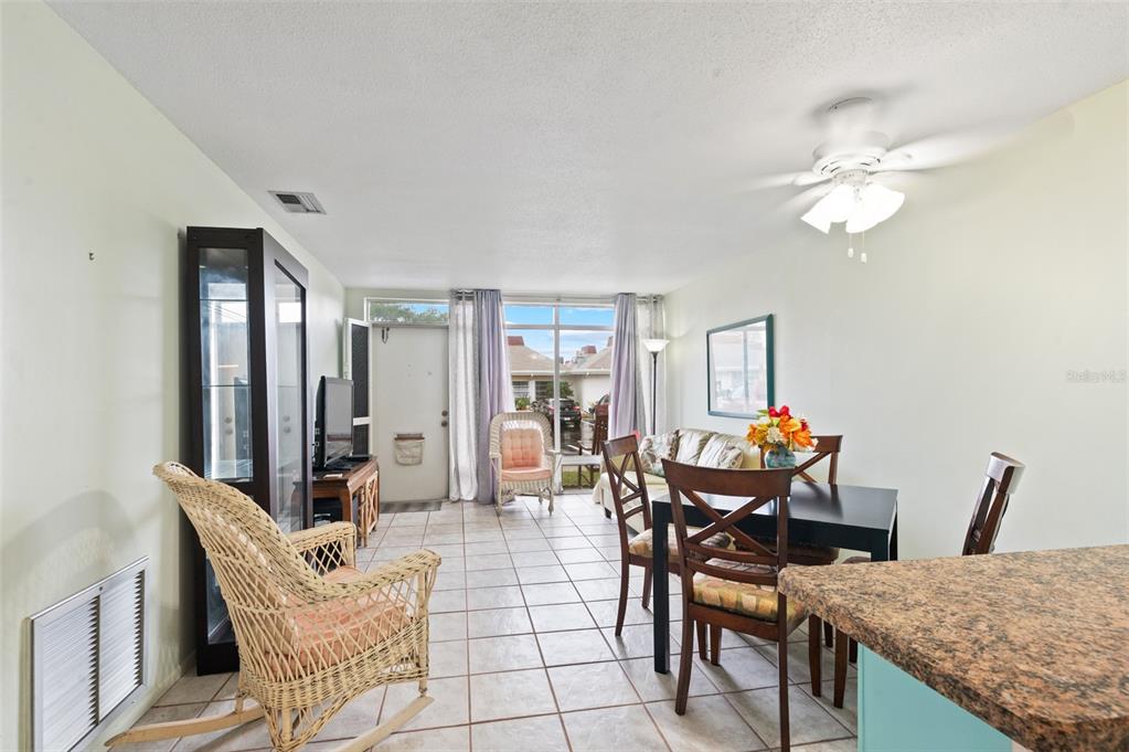 A kitchen with white cabinets, light blue walls, and a dining area in the foreground — 4351 TAHITIAN GARDENS CIRCLE UNIT C, HOLIDAY, FL