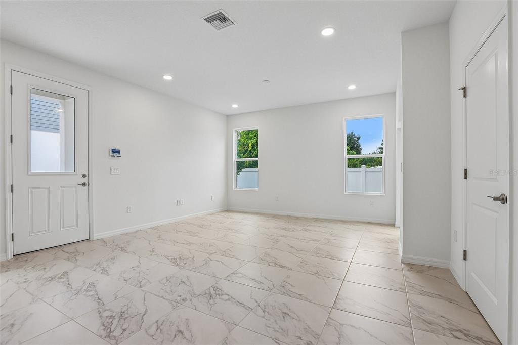 An open-concept kitchen and living area features white cabinetry, marble-look tile flooring, and stairs — 607 SILVER STREAM COURT, BRANDON, FL
