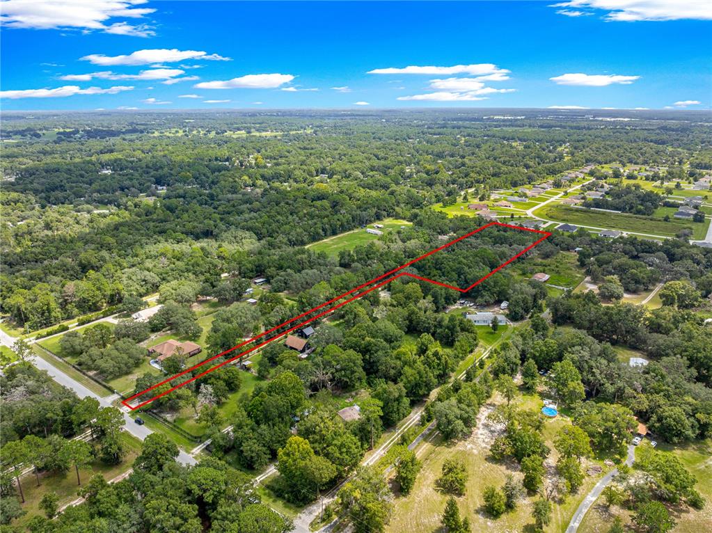 An aerial view shows a large, wooded plot of land outlined in red — 585 NW 117TH COURT, OCALA, FL