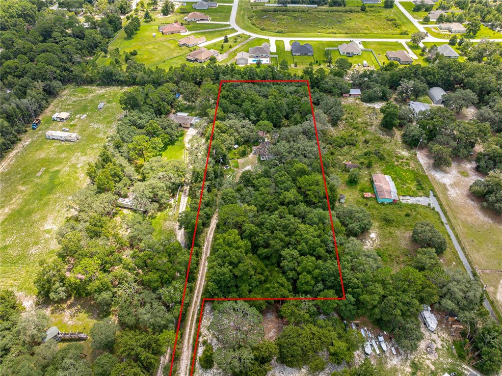 An aerial view shows a wooded lot outlined in red with a dirt driveway — 585 NW 117TH COURT, OCALA, FL