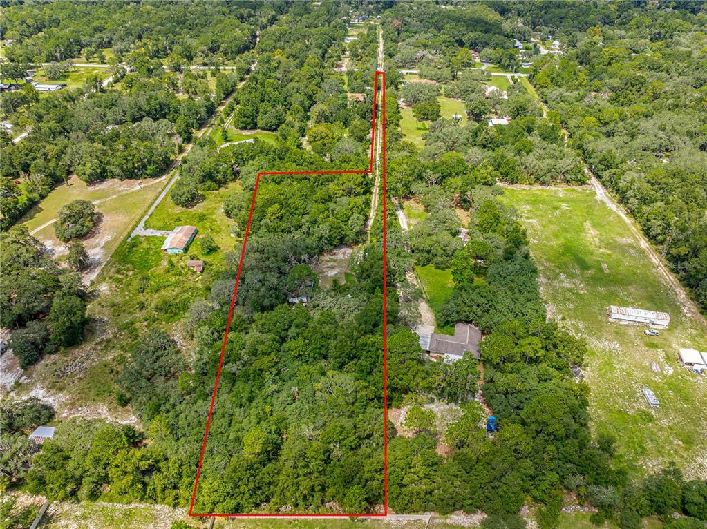 An aerial view shows a wooded lot outlined in red with a long, narrow driveway — 585 NW 117TH COURT, OCALA, FL