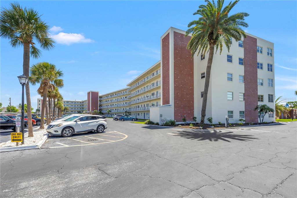 A multi-story apartment building with a brick facade and palm trees in a parking lot — 5575 GULF BOULEVARD UNIT 426, ST PETE BEACH, FL