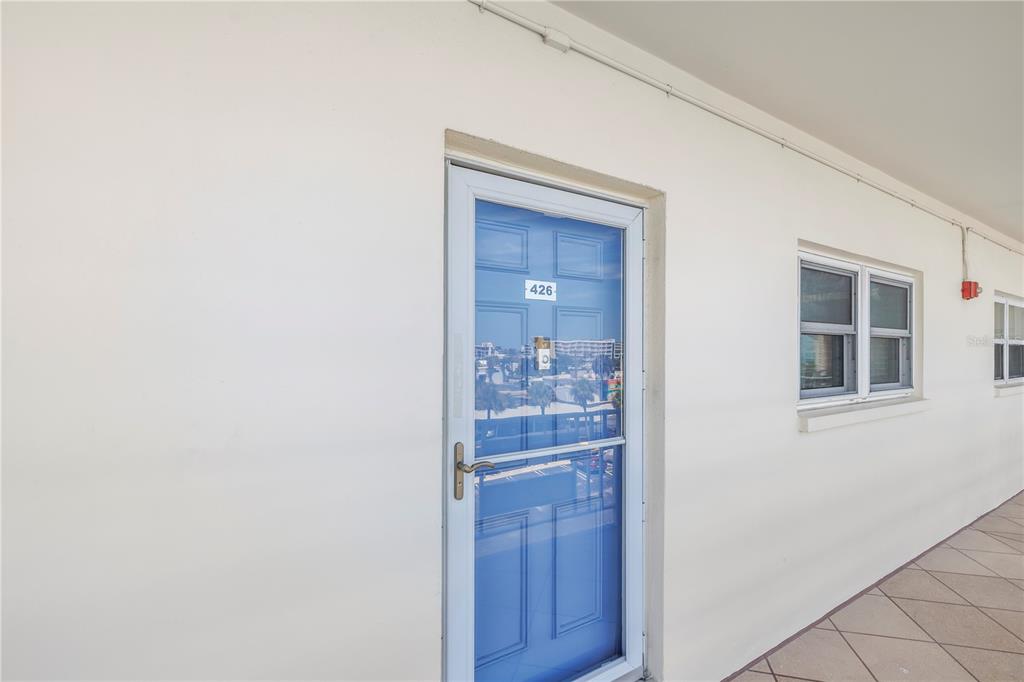 A blue door labeled 426 is set into a plain white exterior wall with windows — 5575 GULF BOULEVARD UNIT 426, ST PETE BEACH, FL