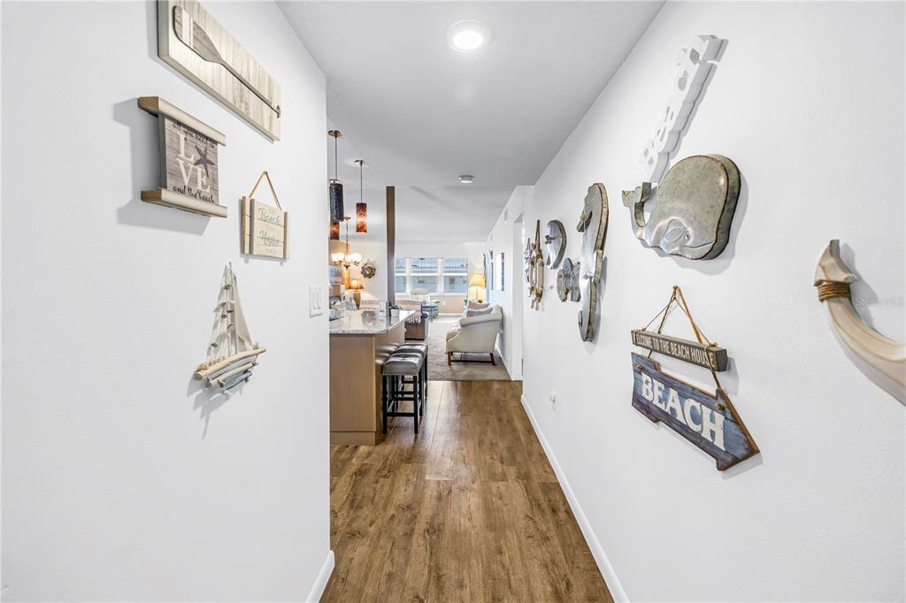 A hallway with beach-themed wall decor leads into an open-concept kitchen and living area — 5575 GULF BOULEVARD UNIT 426, ST PETE BEACH, FL