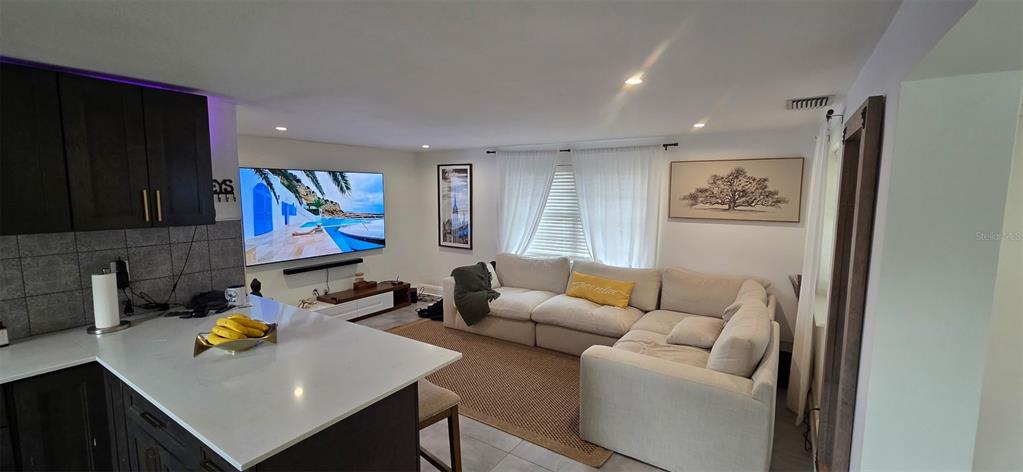 A kitchen island overlooks a living room featuring a large television and a sectional sofa — 146 MARSELLA ROAD, DEBARY, FL