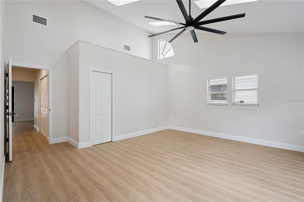 A bright bedroom features light wood-look flooring, a high vaulted ceiling, and a large fan — 201 E MURIEL STREET, ORLANDO, FL