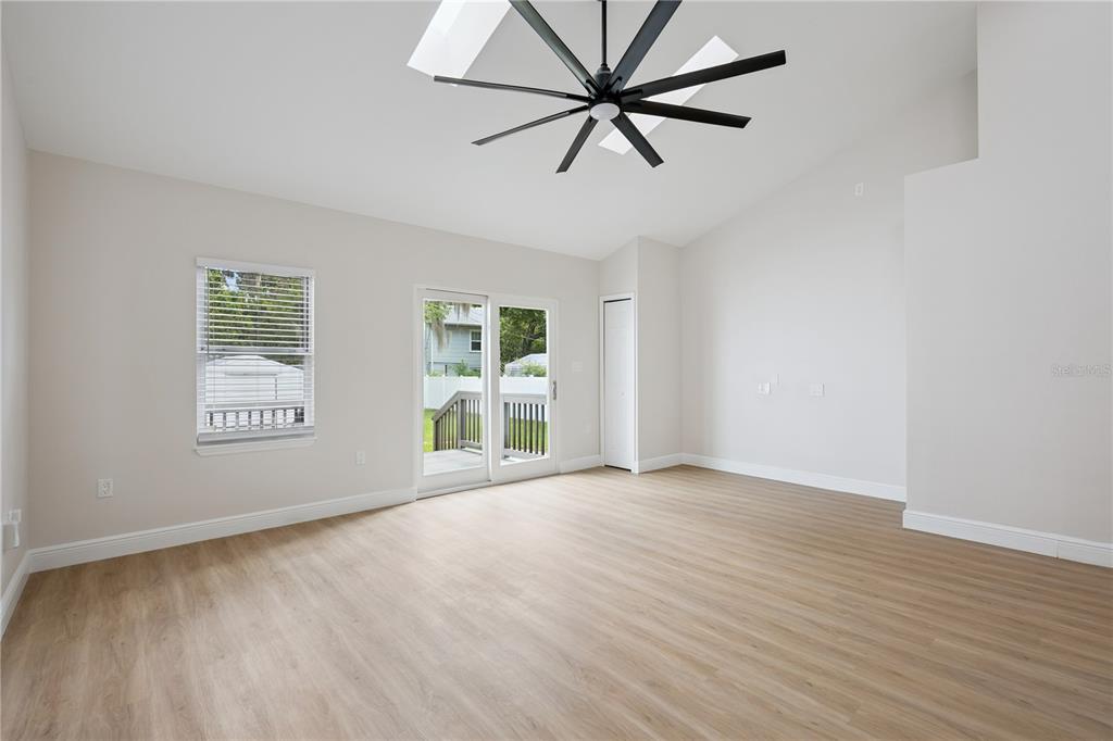 A living room with light wood-look flooring, a ceiling fan, and sliding glass patio doors — 201 E MURIEL STREET, ORLANDO, FL