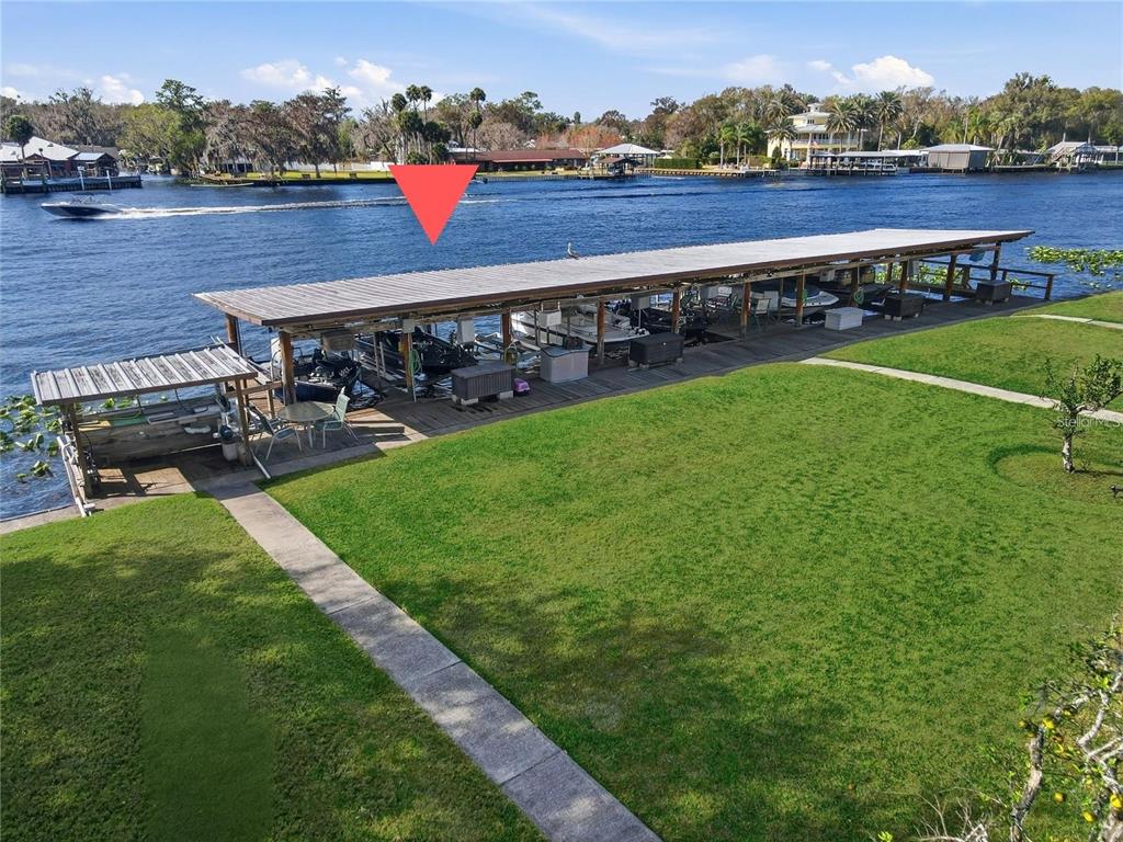 A long, covered boat dock sits along a grassy lawn next to a river — 1640 JUNO TRAIL UNIT 204C, ASTOR, FL