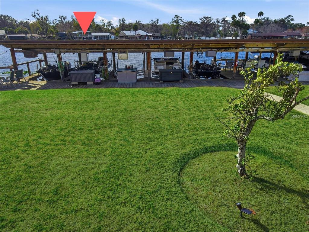 A grassy lawn overlooks a multi-slip boat dock on a lake with houses in the background — 1640 JUNO TRAIL UNIT 204C, ASTOR, FL