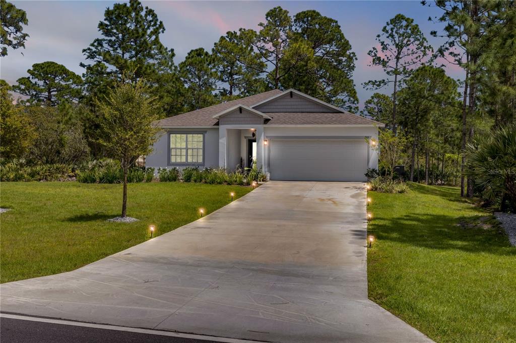 A single-story house with a two-car garage and a concrete driveway lined with lights — 703 VOLCO ROAD, EDGEWATER, FL