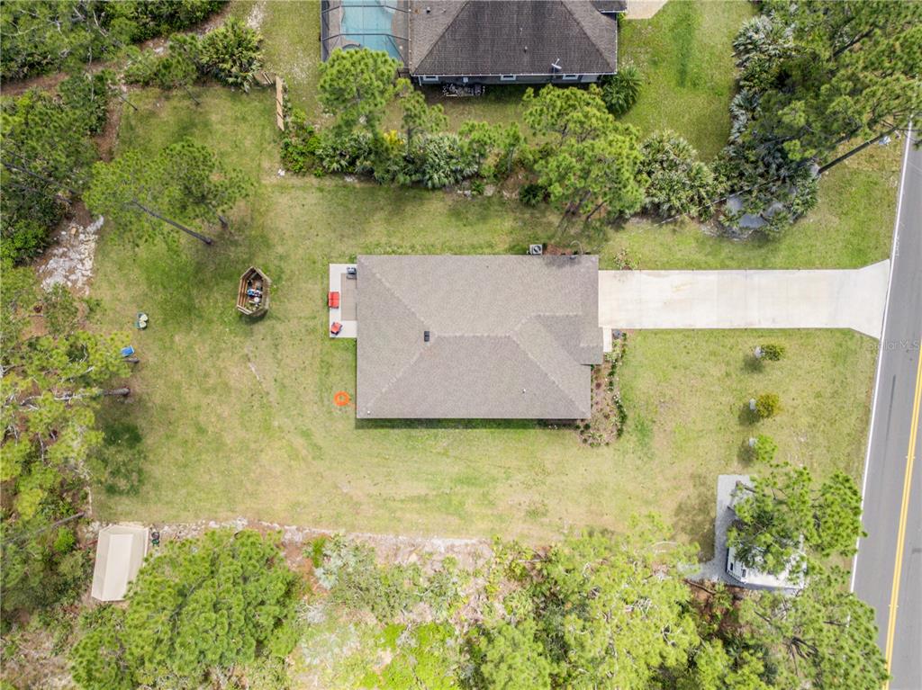 An aerial view shows a single-story house with a driveway, backyard, and surrounding trees — 703 VOLCO ROAD, EDGEWATER, FL