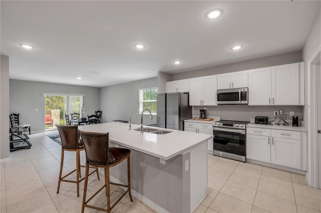 A kitchen with white cabinets, a large island, stainless steel appliances, and tile flooring — 703 VOLCO ROAD, EDGEWATER, FL