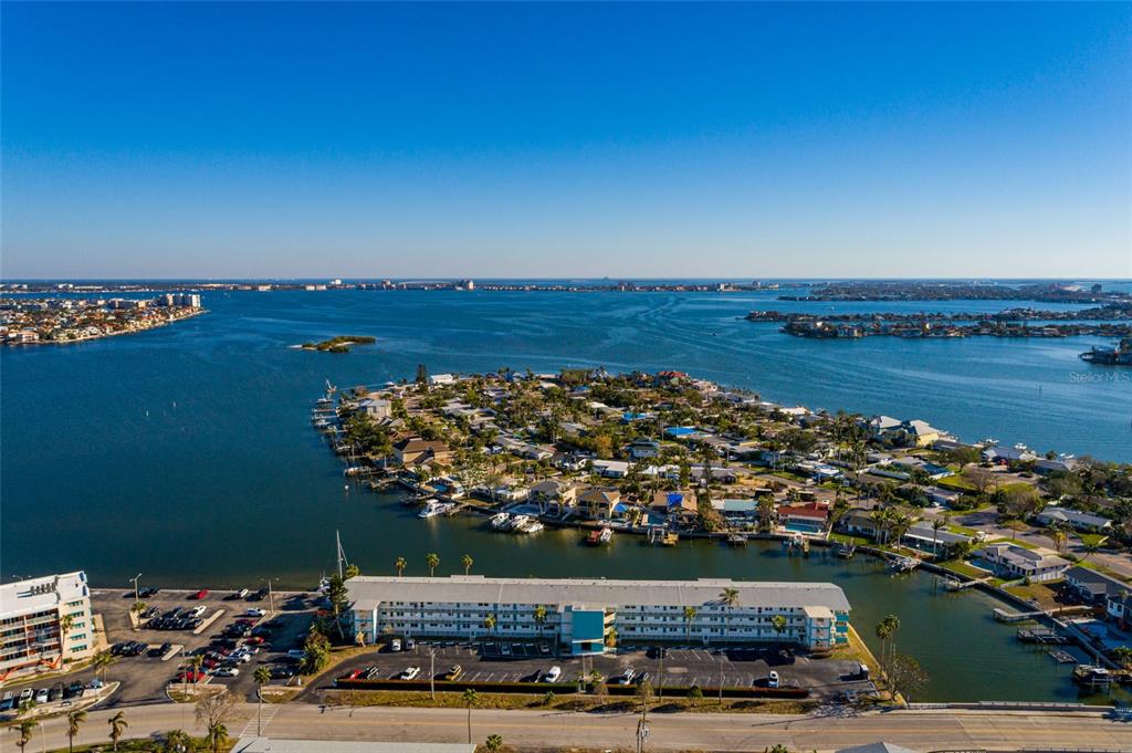 An aerial view shows a multi-story apartment building, a parking lot, and a residential island — 1893 SHORE DRIVE S UNIT 209, SOUTH PASADENA, FL