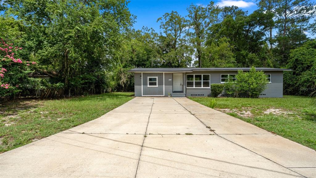A gray, single-story house with a white front door and a concrete driveway — 1015 SE 10TH TERRACE, GAINESVILLE, FL