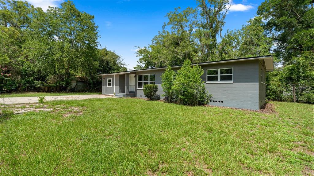 A living room features wood-look flooring, a large entertainment center, and patterned fabric sofas — 1015 SE 10TH TERRACE, GAINESVILLE, FL