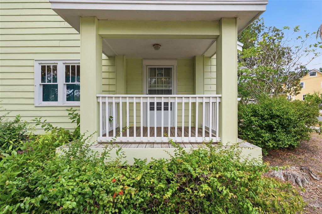A light green house features a covered front porch with a white railing and door — 1747 APACHE TRAIL, CLEARWATER, FL
