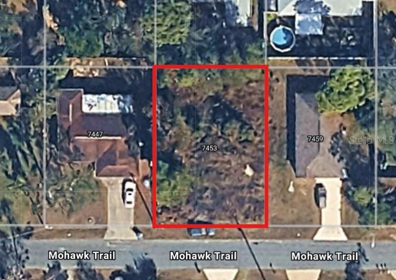 A vacant, overgrown residential lot features a large pile of brown, cut brush in front — 7453 MOHAWK TRAIL, SPRING HILL, FL