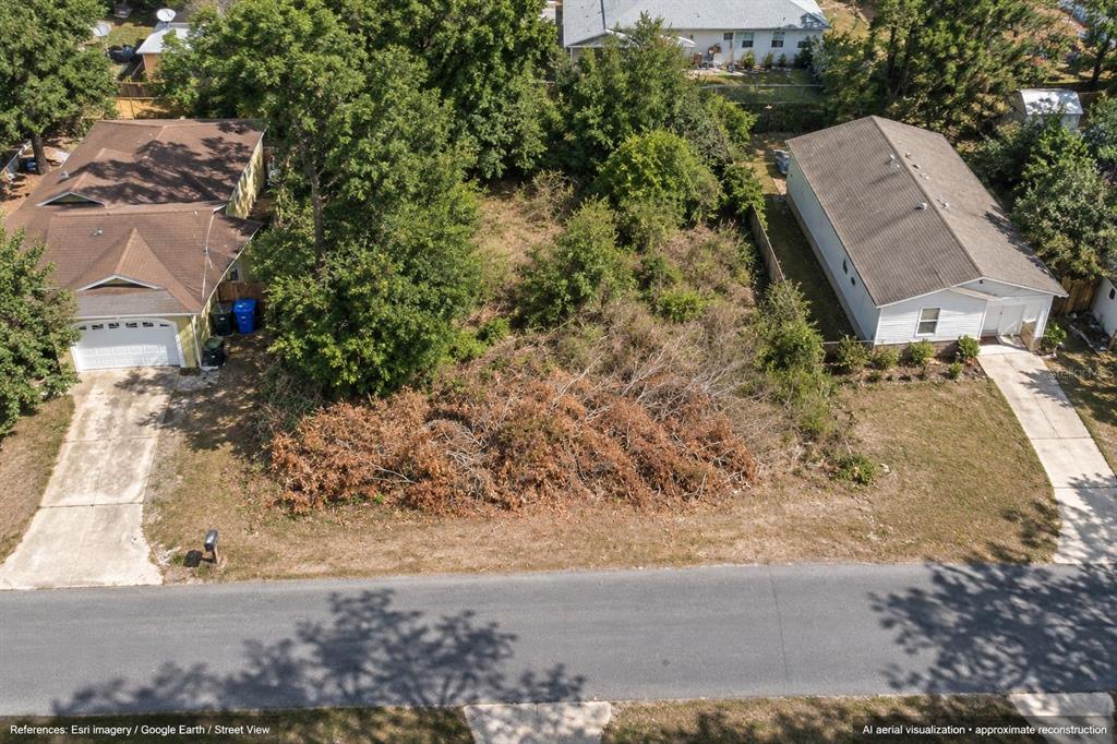 A vacant, grassy lot with trees and brush sits beside a paved road — 7453 MOHAWK TRAIL, SPRING HILL, FL