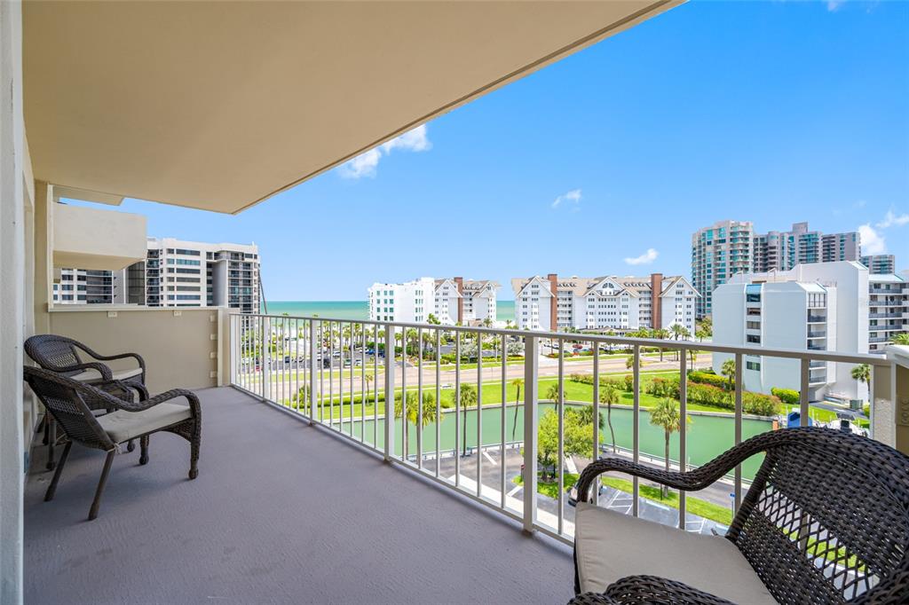 A dining room features a wooden table, upholstered chairs, a chandelier, and light wood flooring — 1621 GULF BOULEVARD UNIT 706, CLEARWATER BEACH, FL