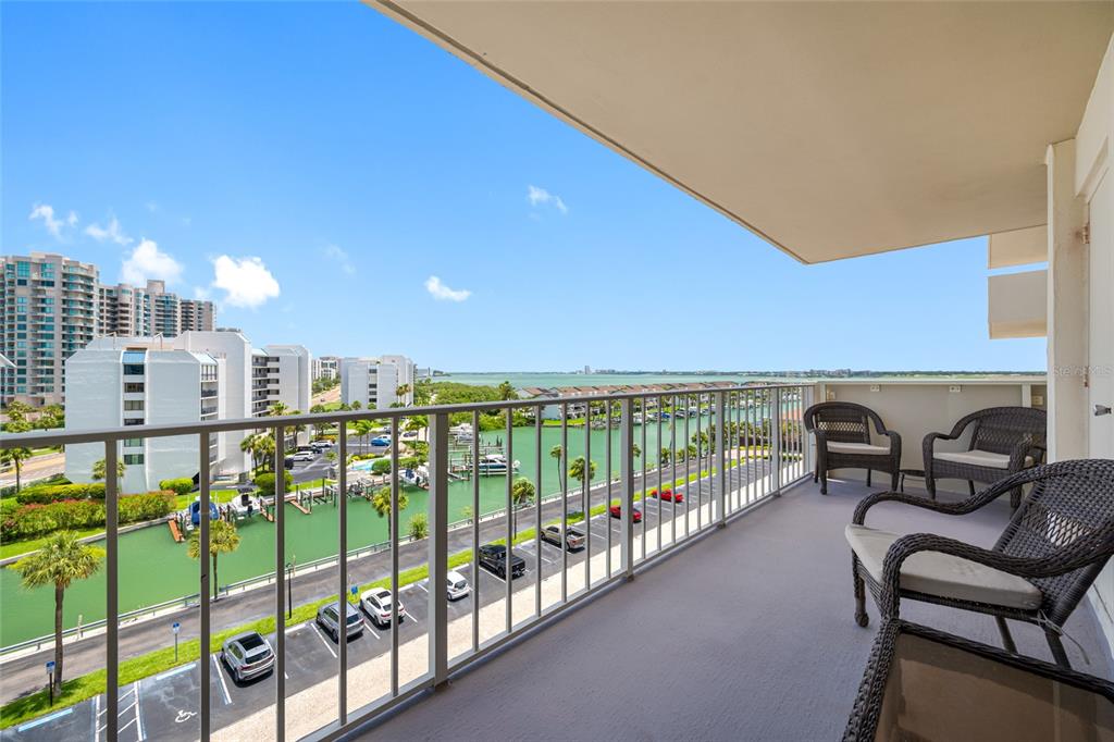 A dining room features a wooden table, upholstered chairs, a chandelier, and light wood flooring — 1621 GULF BOULEVARD UNIT 706, CLEARWATER BEACH, FL