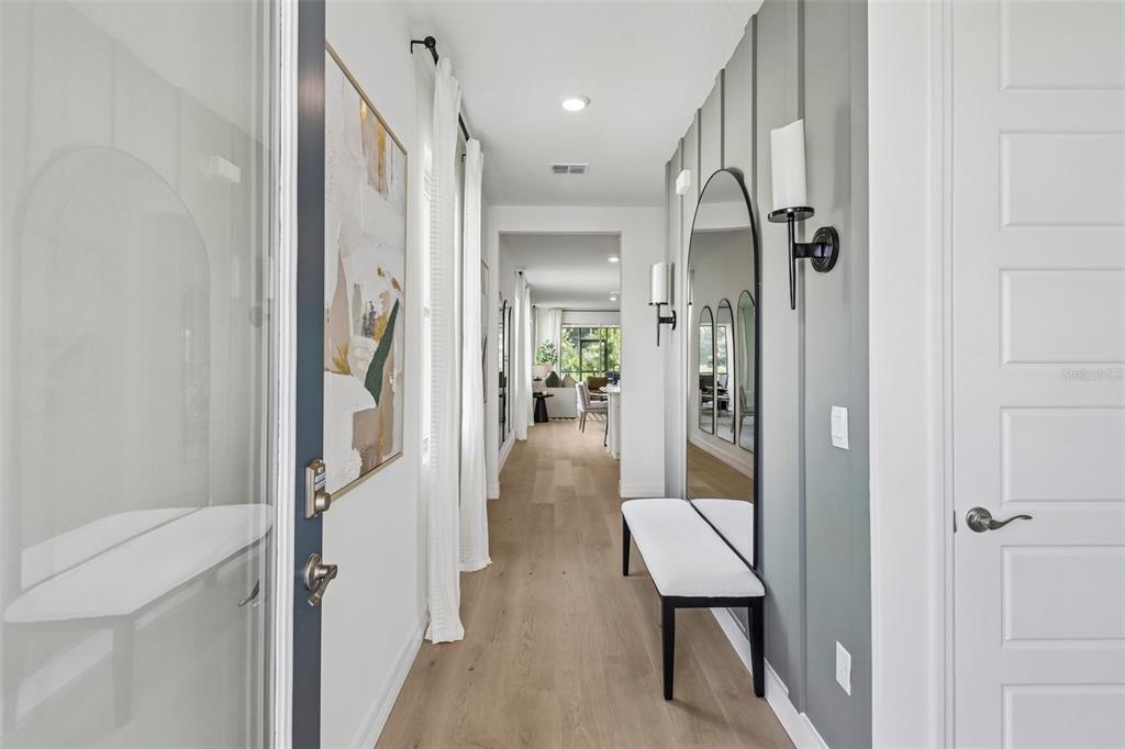 A hallway features light wood floors, a white bench, and a large arched wall mirror — 3945 KENNEBUNK LOOP, MOUNT DORA, FL