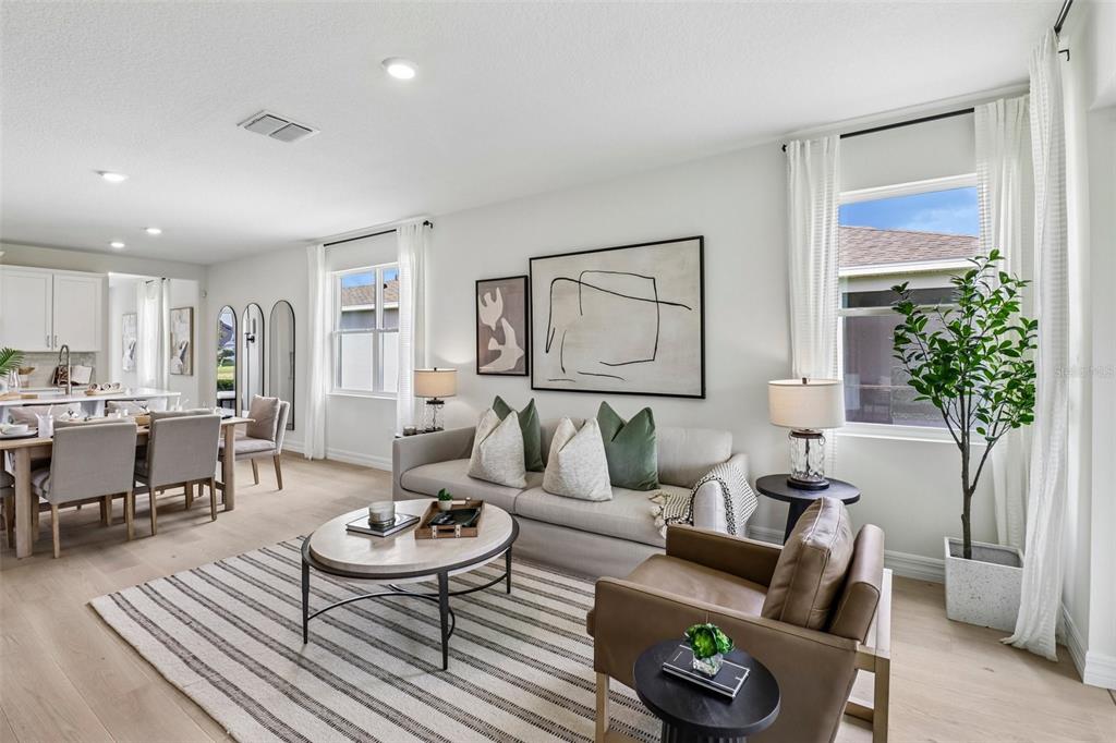 A bright living room features a neutral sofa, leather armchair, and an open-concept dining area — 3945 KENNEBUNK LOOP, MOUNT DORA, FL