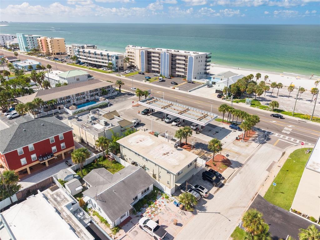 An aerial view shows a gas station, nearby residential buildings, and a beach across the street — 37 144TH AVENUE, MADEIRA BEACH, FL