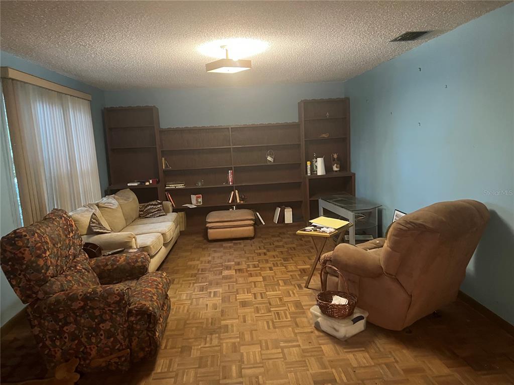 A living room features parquet wood flooring, built-in wooden shelving, and light blue walls — 1024 AVON AVENUE, LAKELAND, FL