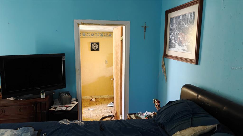 A bedroom with blue walls, a television on a dresser, and a doorway to another room — 1024 AVON AVENUE, LAKELAND, FL