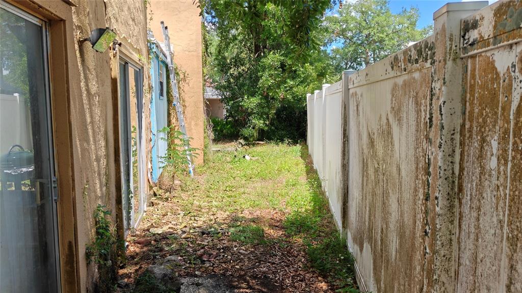 A narrow side yard features a sliding glass door, a ladder, and a weathered vinyl fence — 1024 AVON AVENUE, LAKELAND, FL