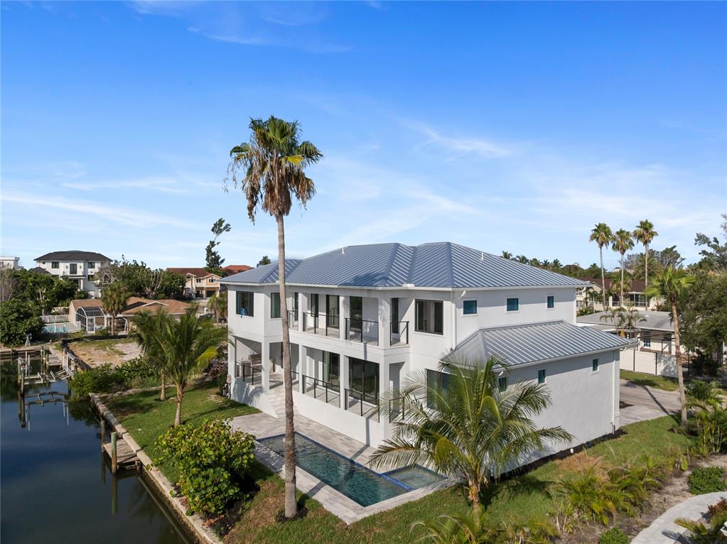 A multi-story white house with a metal roof, a pool, and a canal-side backyard — 530 DE NARVAEZ DRIVE, LONGBOAT KEY, FL