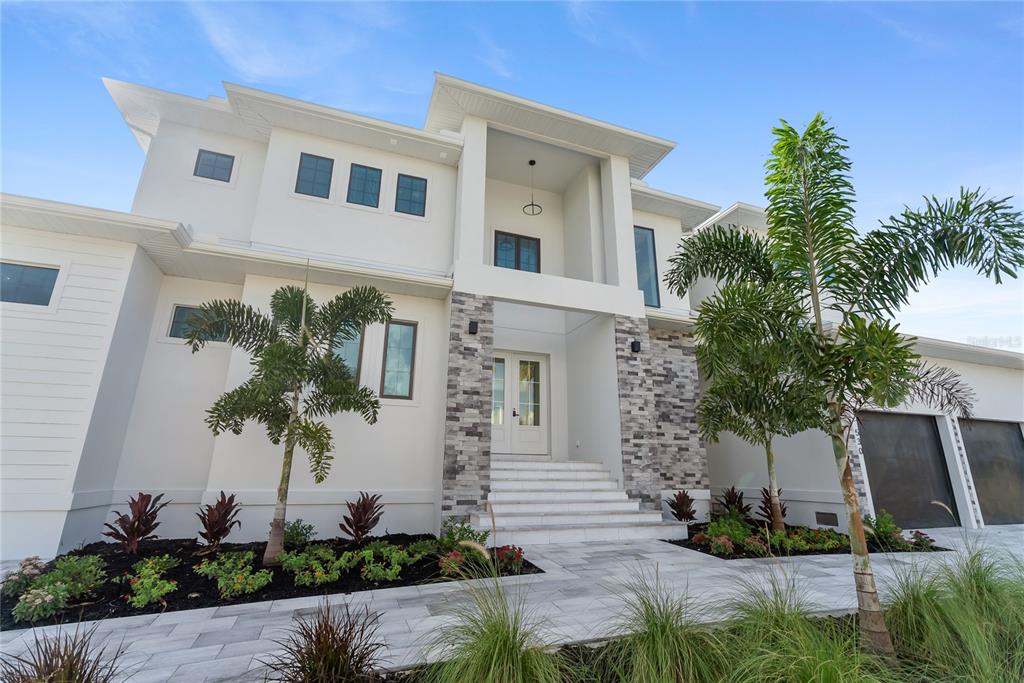 A modern two-story house features white stucco walls, stone accents, and a front entryway staircase — 530 DE NARVAEZ DRIVE, LONGBOAT KEY, FL