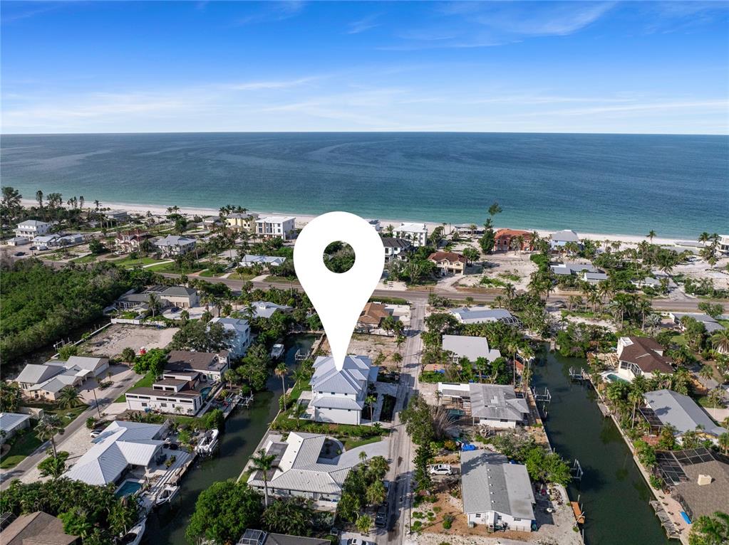 An aerial view shows a coastal neighborhood with houses situated along canals near the beach — 530 DE NARVAEZ DRIVE, LONGBOAT KEY, FL