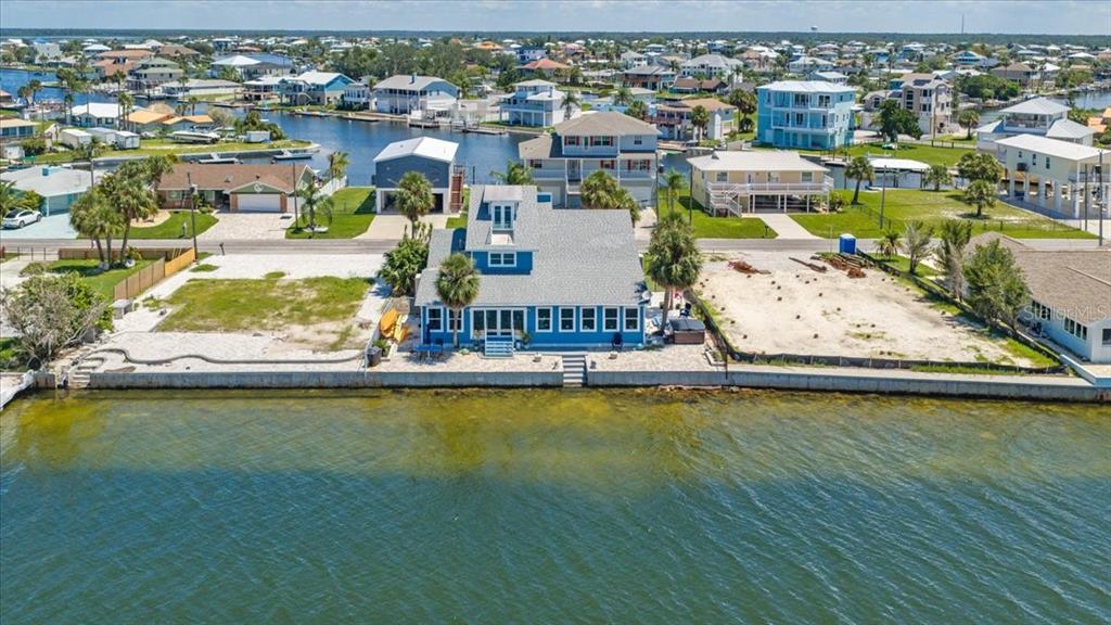 An aerial view shows a blue waterfront house with a gray roof and sandy lots — 3200 GULF WINDS CIRCLE, HERNANDO BEACH, FL