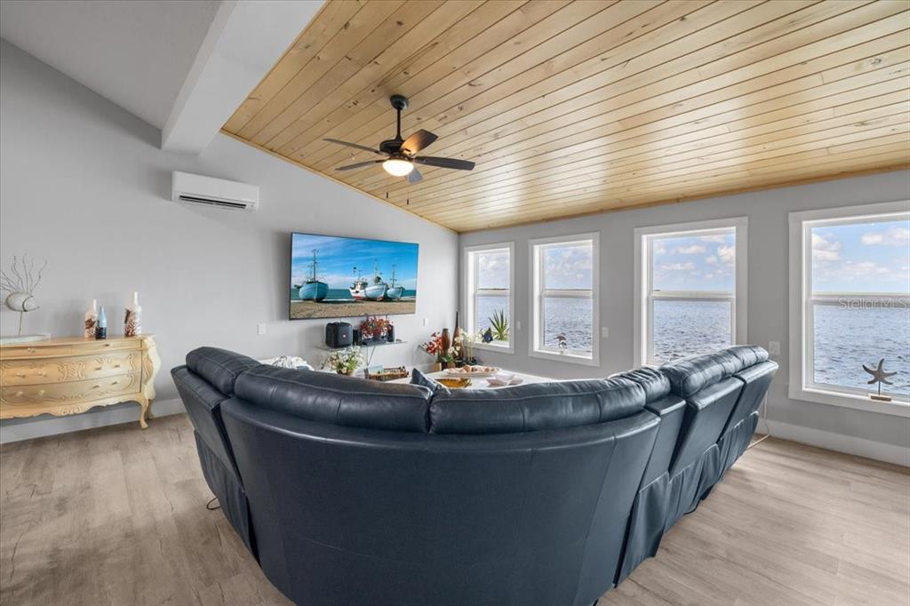 A living room features a vaulted wood-paneled ceiling, a large sectional sofa, and water views — 3200 GULF WINDS CIRCLE, HERNANDO BEACH, FL