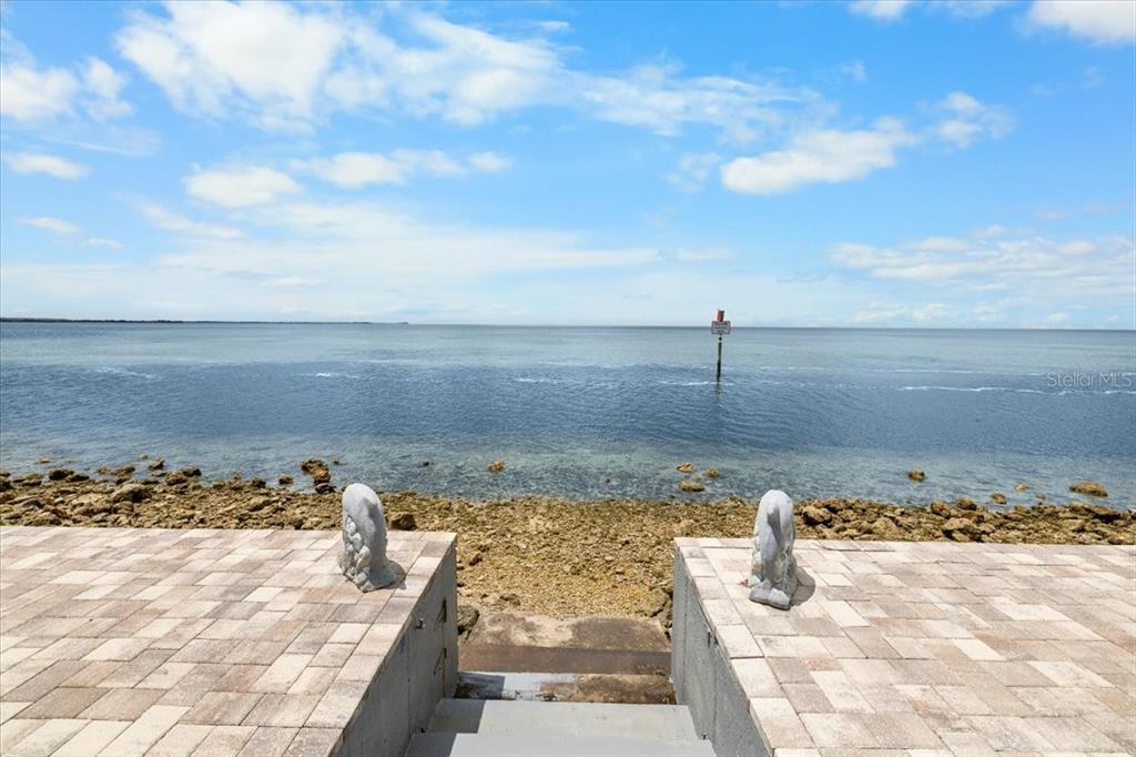 A stone patio with two dolphin statues overlooks a rocky shoreline and the open ocean — 3200 GULF WINDS CIRCLE, HERNANDO BEACH, FL