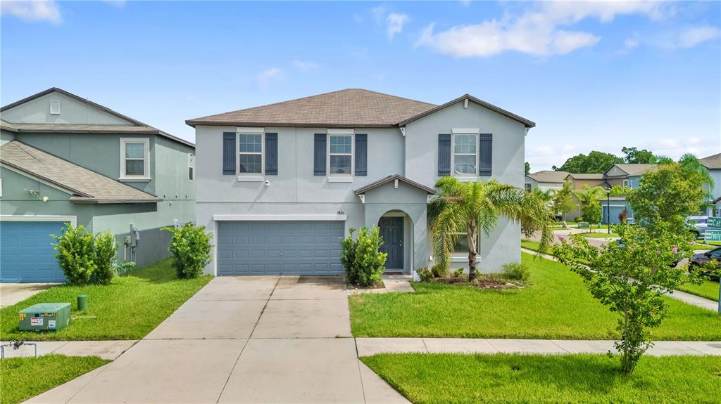 A two-story suburban house with a gray exterior, a two-car garage, and a front lawn — 7420 PEARLY EVERLASTING AVENUE, TAMPA, FL