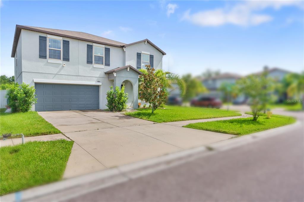 A two-story suburban house with a gray stucco exterior, a two-car garage, and a driveway — 7420 PEARLY EVERLASTING AVENUE, TAMPA, FL