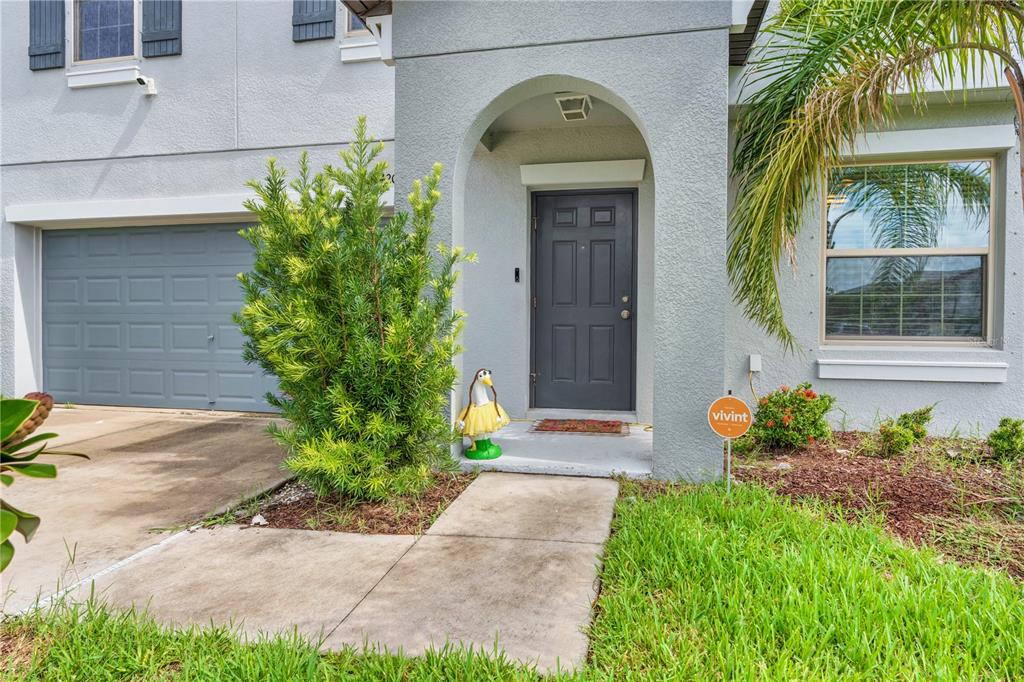 A dark blue front door is centered on a concrete porch with a decorative goose — 7420 PEARLY EVERLASTING AVENUE, TAMPA, FL