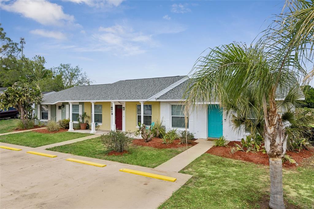 A single-story duplex with a yellow and white exterior, a teal door, and parking spaces — 220 RIDGECREST LOOP, MINNEOLA, FL