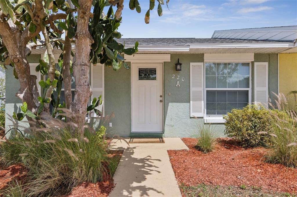 The exterior of a single-story home features a white front door, shutters, and landscaping — 220 RIDGECREST LOOP, MINNEOLA, FL