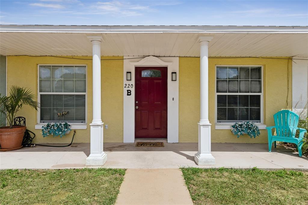 The exterior of a yellow house features a red front door and two white columns — 220 RIDGECREST LOOP, MINNEOLA, FL